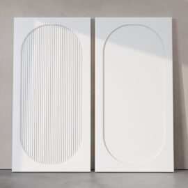 Two Celine Oval Fluted Panel Barn Doors, each in white; the door on the left showcases vertical grooves inside its oval design, whereas the smooth oval design decorates the door on the right. Both doors are positioned against a light gray wall.