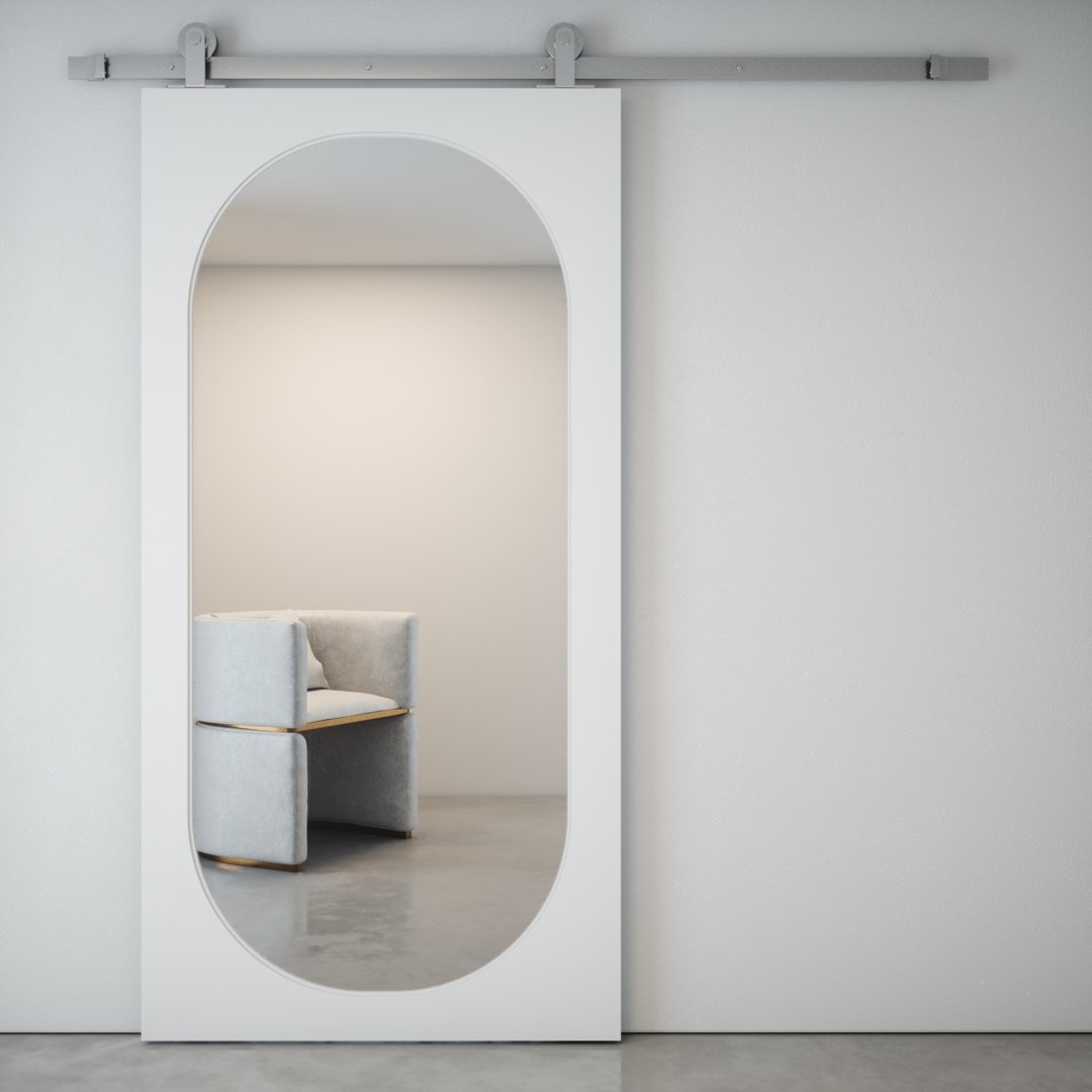 CELINE-OVAL-MIRROR-BARN-DOOR-silver-hardware-Main.jpg The Celine Oval Mirror Barn Door, in white, reflects a contemporary beige chair in a minimalist room featuring light grey walls and a concrete floor.