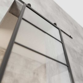 Close-up of a French Casement 4-Panel Barn Door with a metal frame installed on a concrete wall. The door is slightly open, and the image is taken from a low angle.