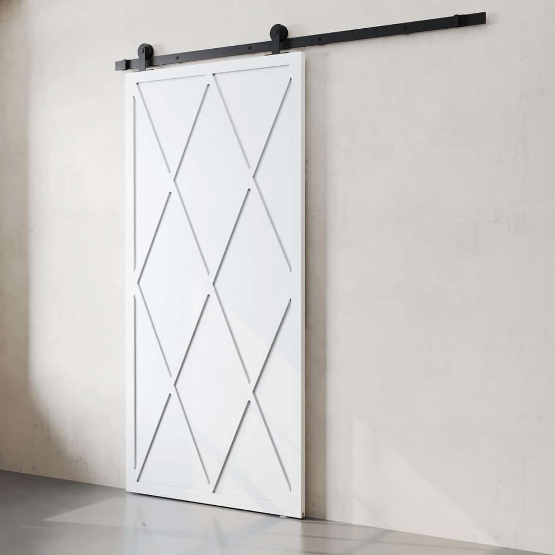 The Lynx Barn Door, featuring a white finish with a diamond pattern design, is mounted on a black track against a plain white wall.