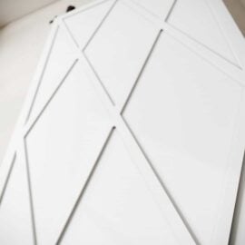 The Lynx Barn Door features a geometric pattern with intersecting diagonal and vertical lines in a white finish.