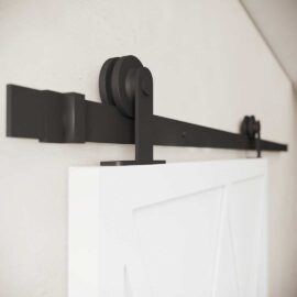 Close-up of the Lynx Barn Door black metal sliding hardware set mounted on a white wall with a partially visible door.