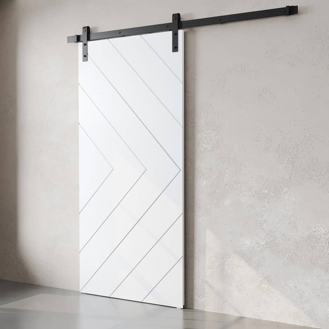 The Prestige Barn Door, featuring a modern geometric design in white, is mounted on a sleek black sliding track against a concrete wall.