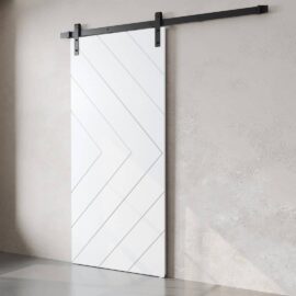 The Prestige Barn Door, featuring a modern geometric design in white, is mounted on a sleek black sliding track against a concrete wall.