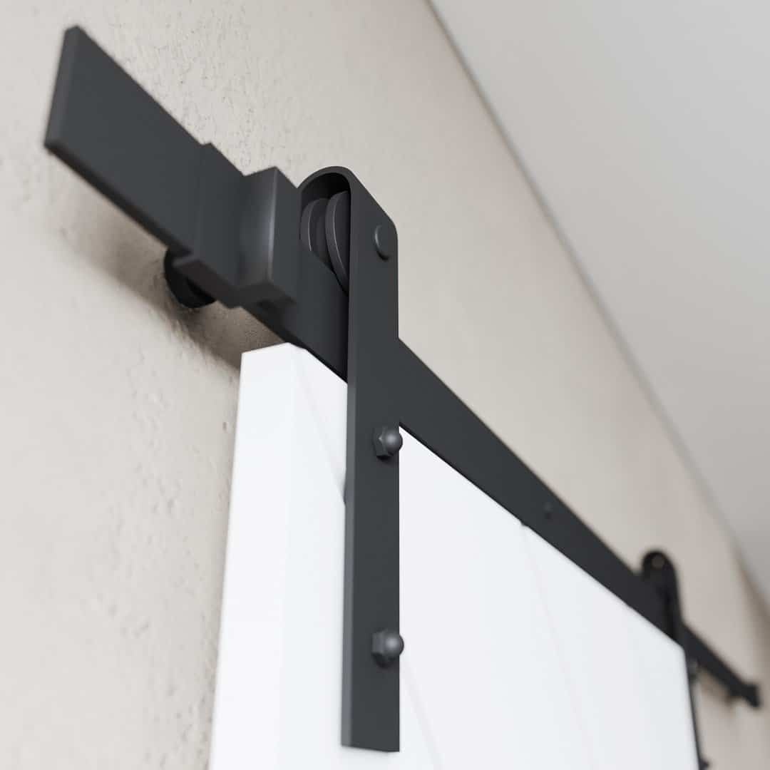 PRESTIGE-WHITE-4.jpg Close-up of the Prestige Barn Door hardware in black, featuring a white door mounted on a beige wall.