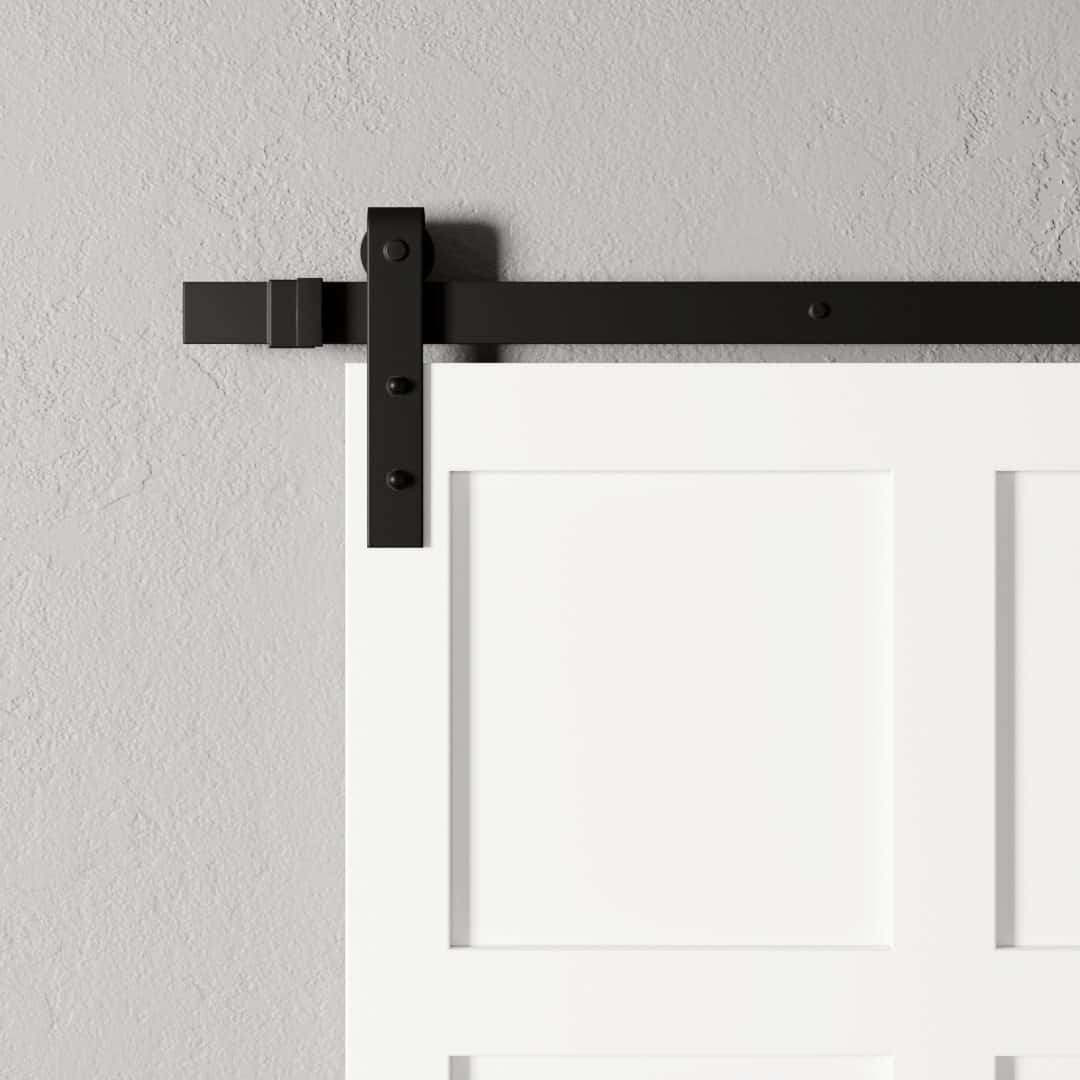 Urban-Woodcraft-8-Panel-Barn-Door-White-3.jpg Close-up of the 8-Panel Barn Door, boasting white panels and black metal hardware, elegantly mounted on a light gray textured wall.