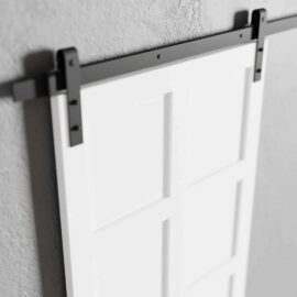 A close-up view of an 8-Panel Barn Door in white, mounted on a sleek black track system against a textured gray wall.
