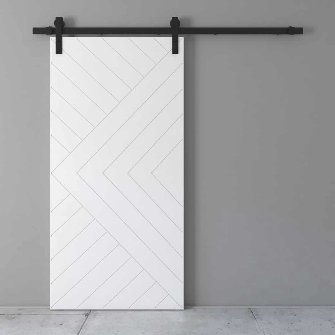 The Arctic Barn Door, featuring a chevron pattern, is mounted on a black track system against a gray wall. The floor is partially visible.