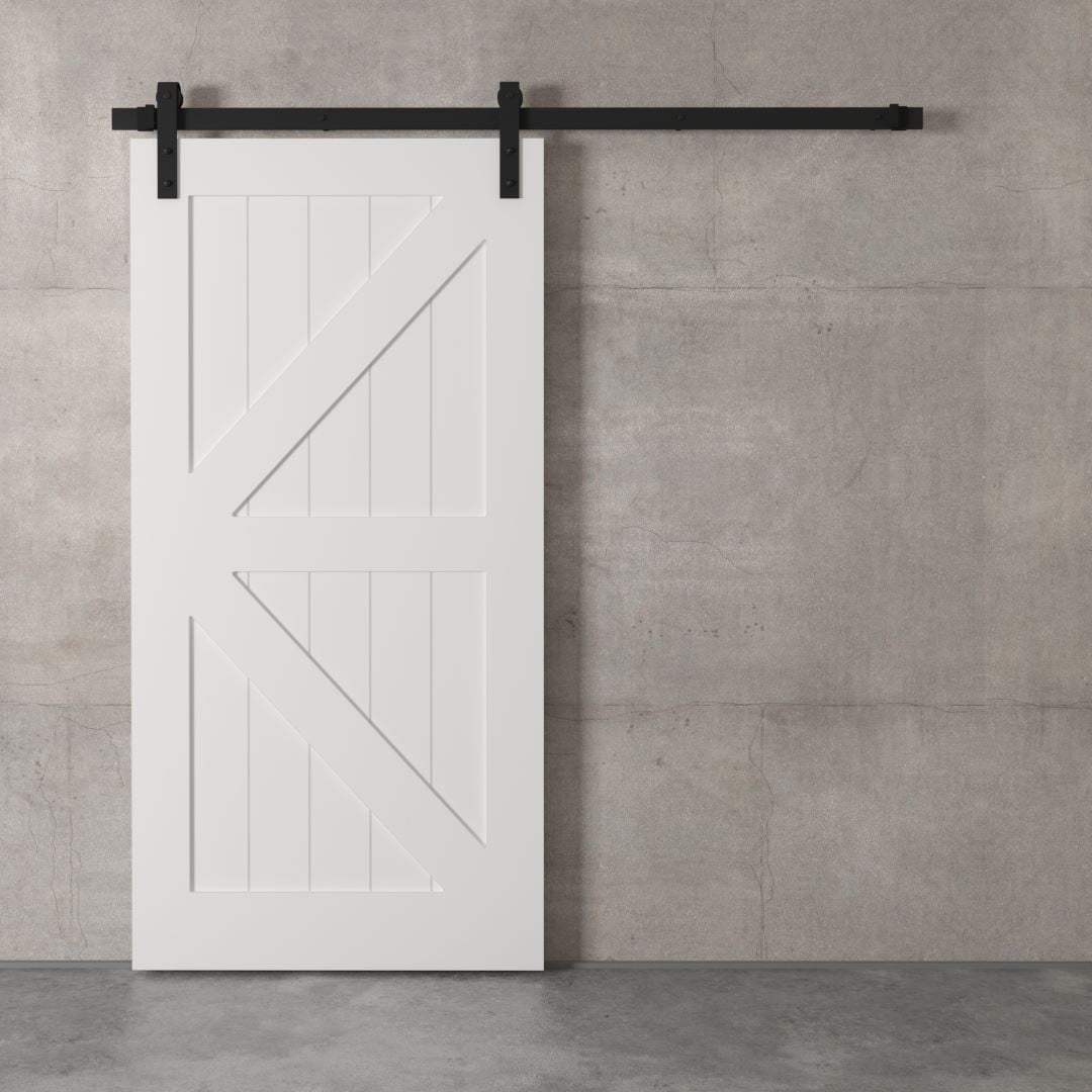 Urban-Woodcraft-British-Brace-White-Barn-Door-2.jpg A white British brace barn door is mounted on a black metal track against a plain concrete wall.