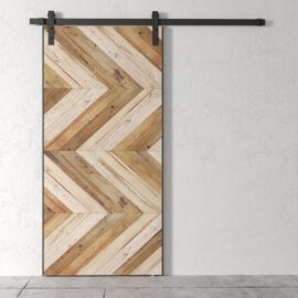 A Scandi Chevron Barn Door featuring a chevron wood pattern is mounted on a black metal rail against a plain white wall.