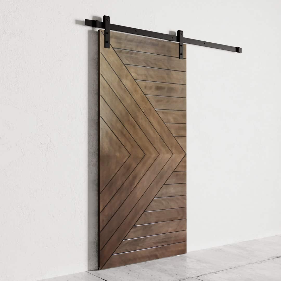 The Dawson Barn Door is a modern wooden sliding barn door featuring a geometric chevron pattern, mounted on a black metal track against a white wall.