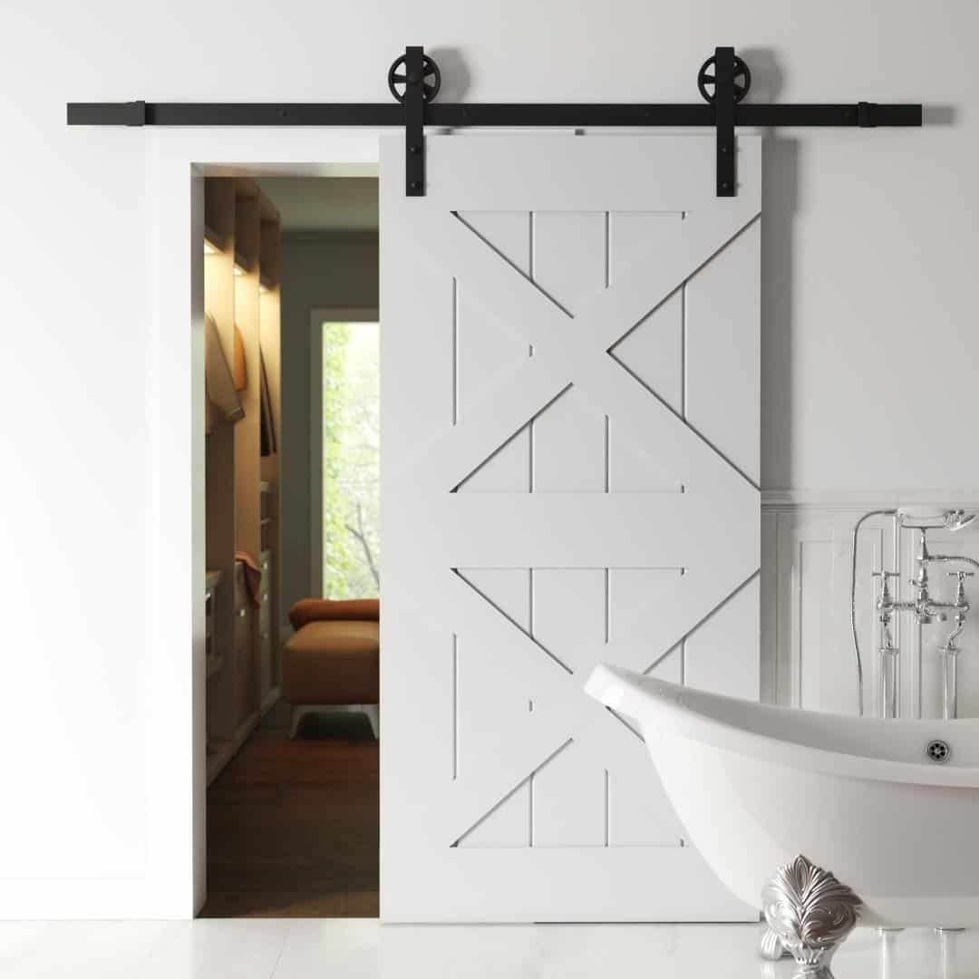 A Double X Barn Door with black hardware is partially open, revealing a hallway leading to another room with furniture. In the foreground, a white clawfoot bathtub is visible.