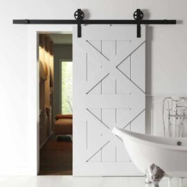 A Double X Barn Door with black hardware is partially open, revealing a hallway leading to another room with furniture. In the foreground, a white clawfoot bathtub is visible.