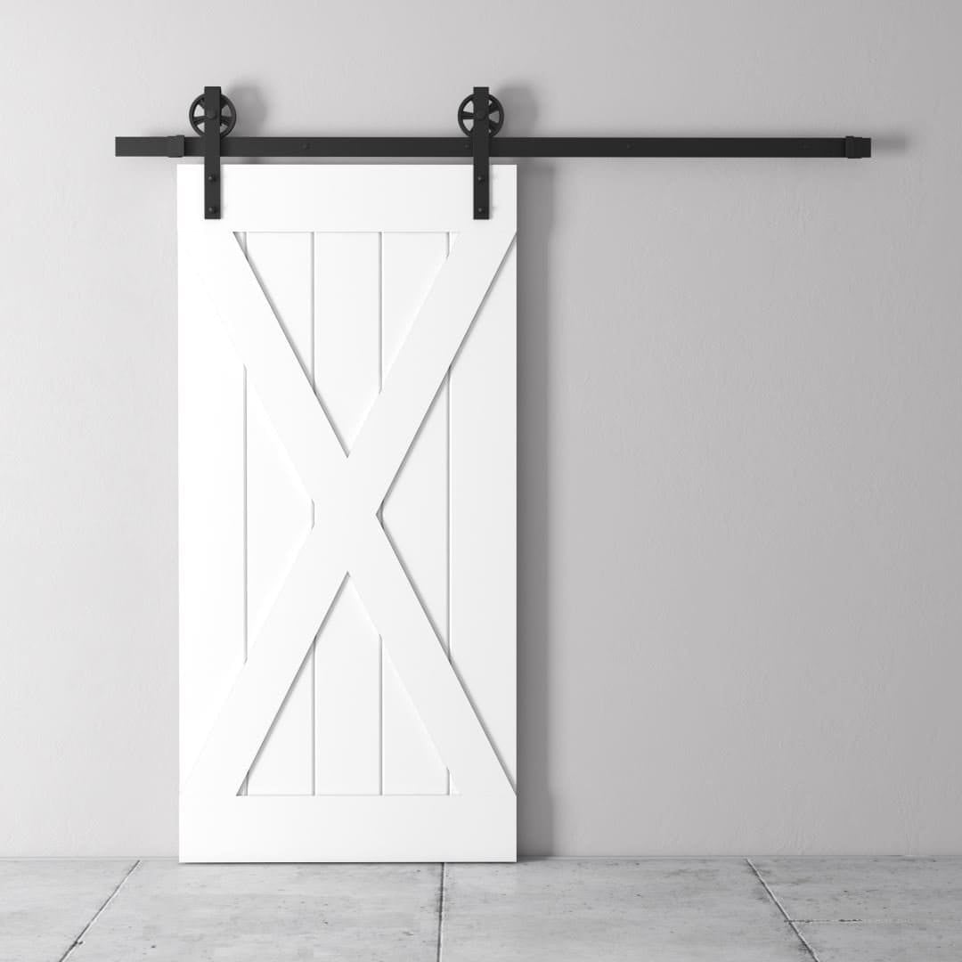 Urban-Woodcraft-Grand-X-White-Barn-Door-3.jpg The Grand X Barn Door, a white wooden design equipped with a black sliding track, is mounted on a light gray wall above a concrete floor.