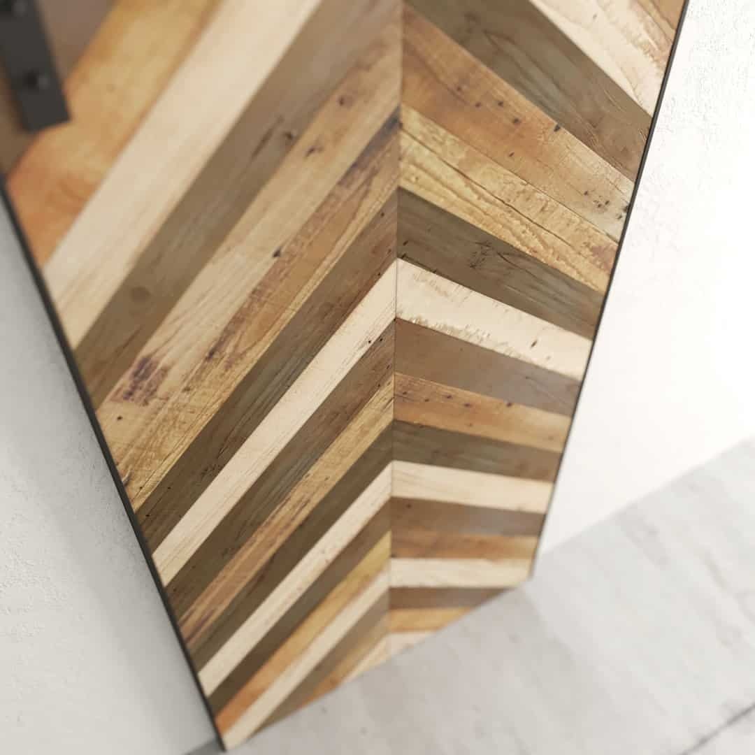 Close-up of the Wolves Herringbone Barn Door, featuring a chevron pattern made from alternating light and dark wooden planks, in a modern space with white walls and a light gray floor.