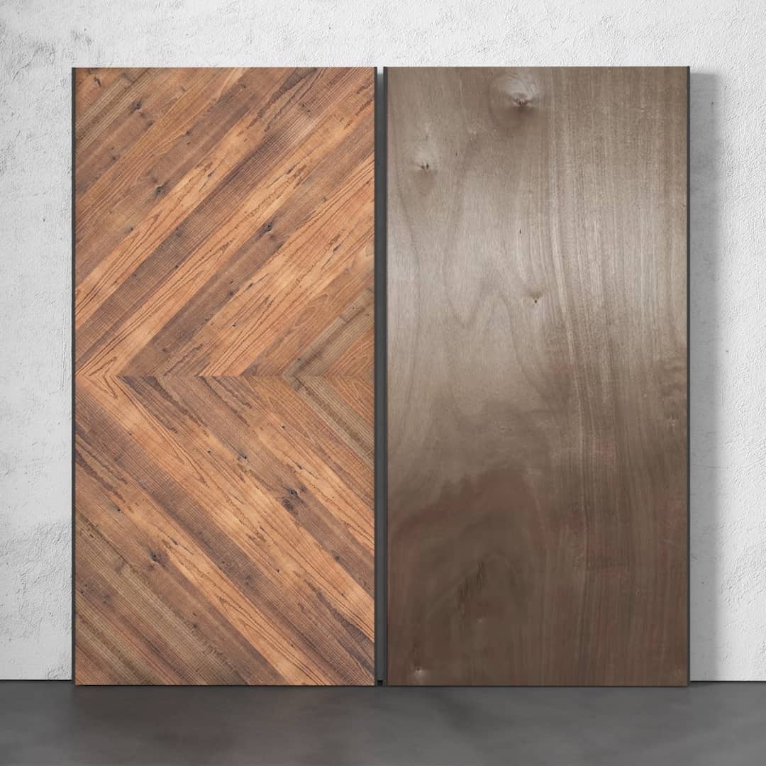 Urban-Woodcraft-Lucas-40in-Reclaimed-Wood-Arrow-Barn-Door-4.jpg Two vertical wooden panels stand side by side; the left panel, Lucas Reclaimed Wood Arrow Barn Door, showcases a herringbone pattern with a variety of wood tones, whereas the right panel displays a smooth, uniform brown surface. Both panels are set against a light wall.