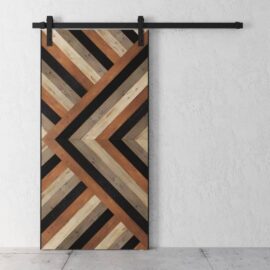 The Cali Malibu Barn Door features a geometric chevron pattern in natural, dark brown, and black finishes, mounted on a black metal track against a white textured wall.