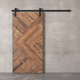 The Malibu Barn Door, featuring a wooden design with a chevron pattern, is mounted on a sleek black sliding track against a concrete wall.