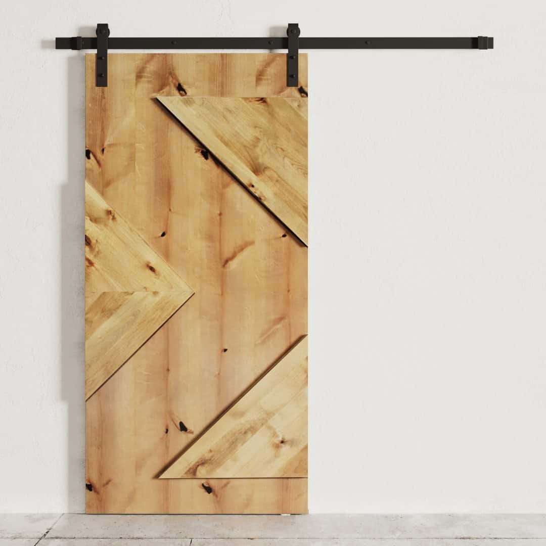 The Raised Arrow Head Barn Door, featuring diagonal plank accents, is mounted on a black metal track against a white wall.