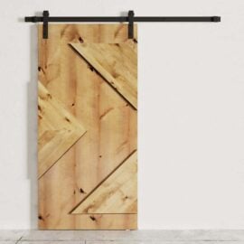 The Raised Arrow Head Barn Door, featuring diagonal plank accents, is mounted on a black metal track against a white wall.