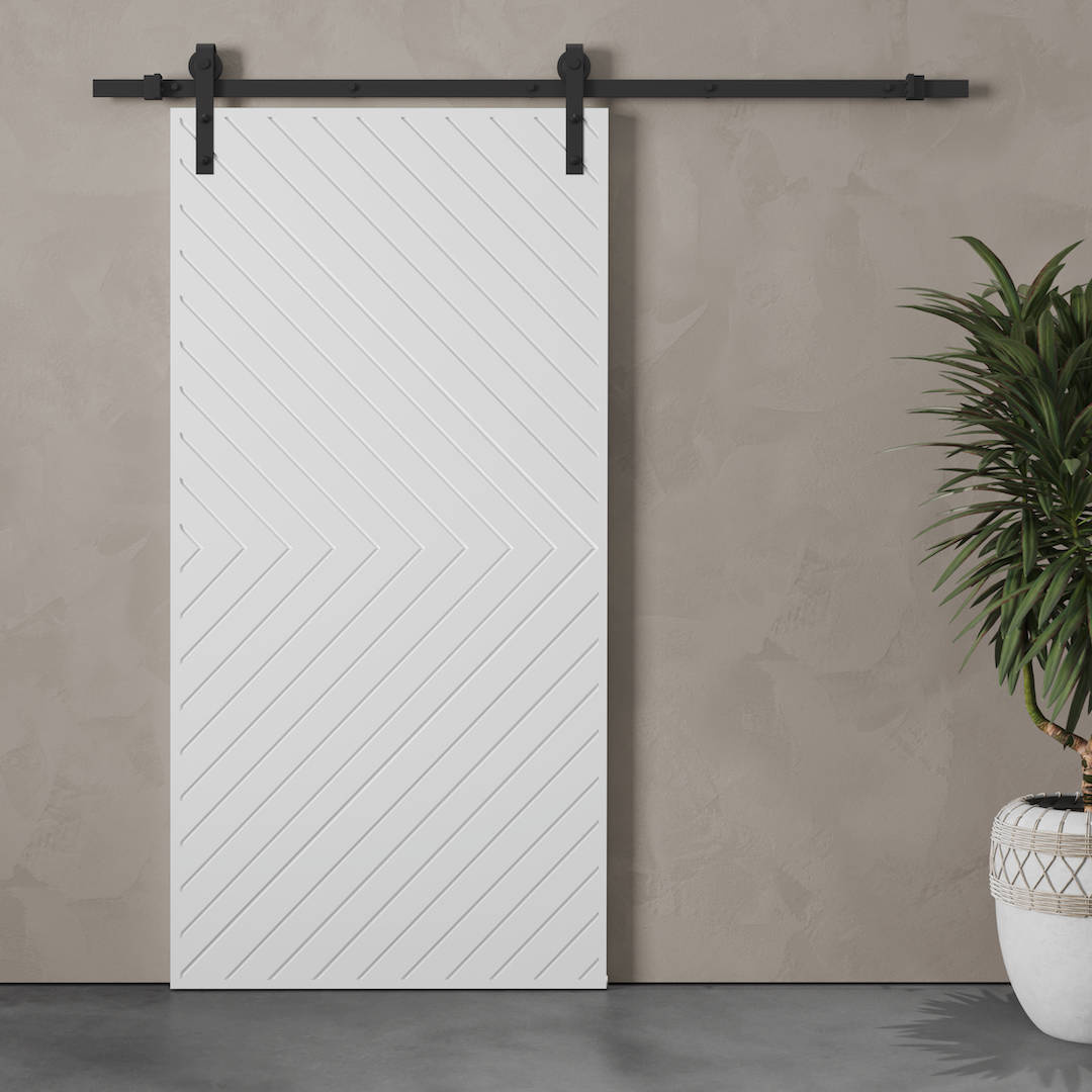 The Venice Arrow Barn Door, featuring a white Herringbone pattern and mounted on a sleek black metal rail, is accompanied by a potted plant in a stylish white pot adorned with gold accents.