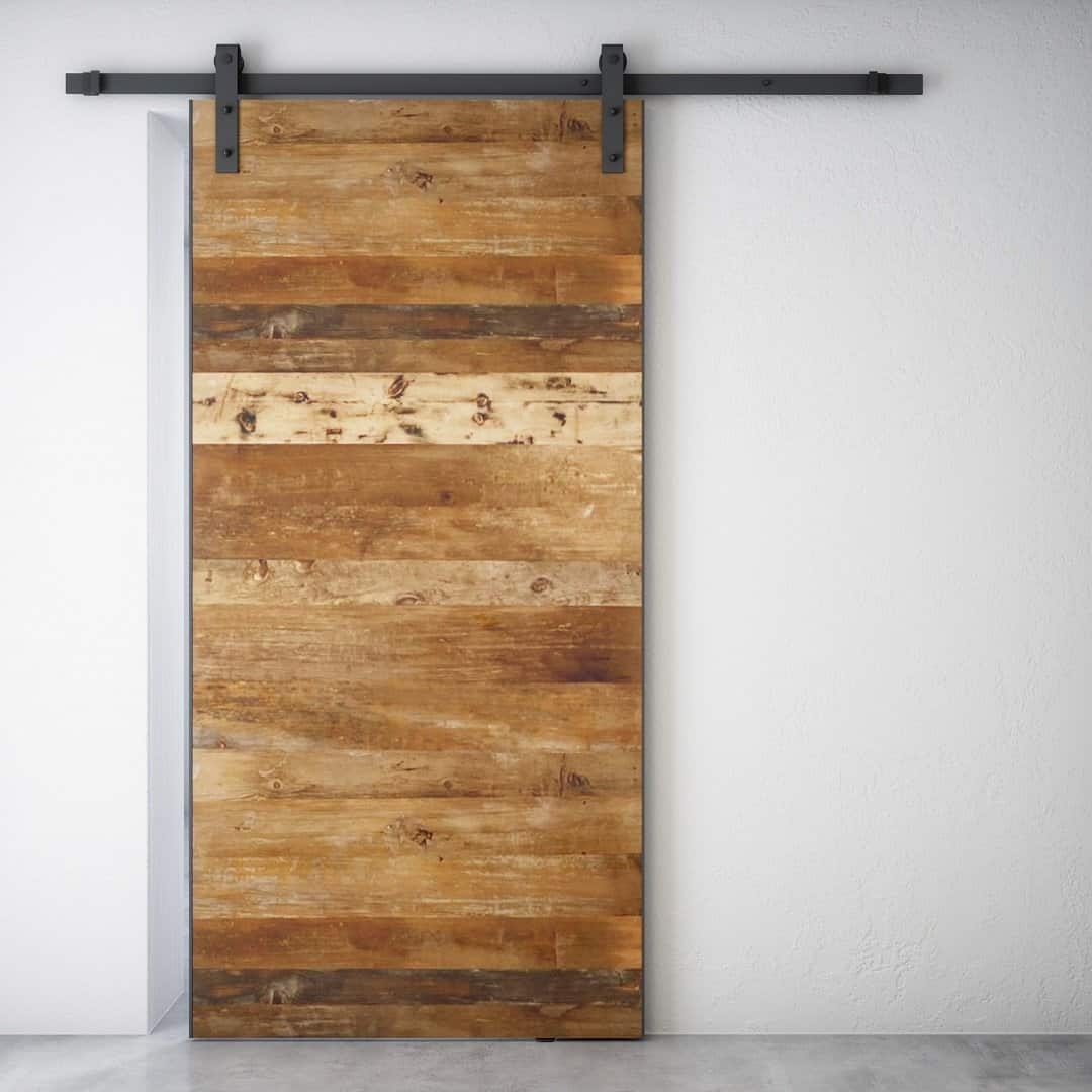 The Maison Barn Door, featuring horizontal planks and metal hardware, installed on a white wall.