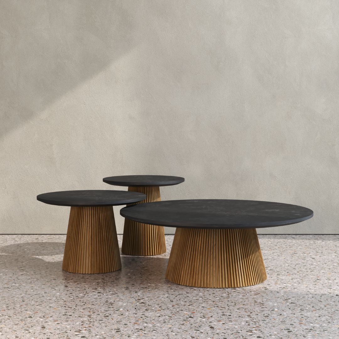 Three round coffee tables with black tops and ribbed wooden bases are elegantly placed on a speckled terrazzo floor against a textured beige wall, blending a touch of Osaka chic into the setting.